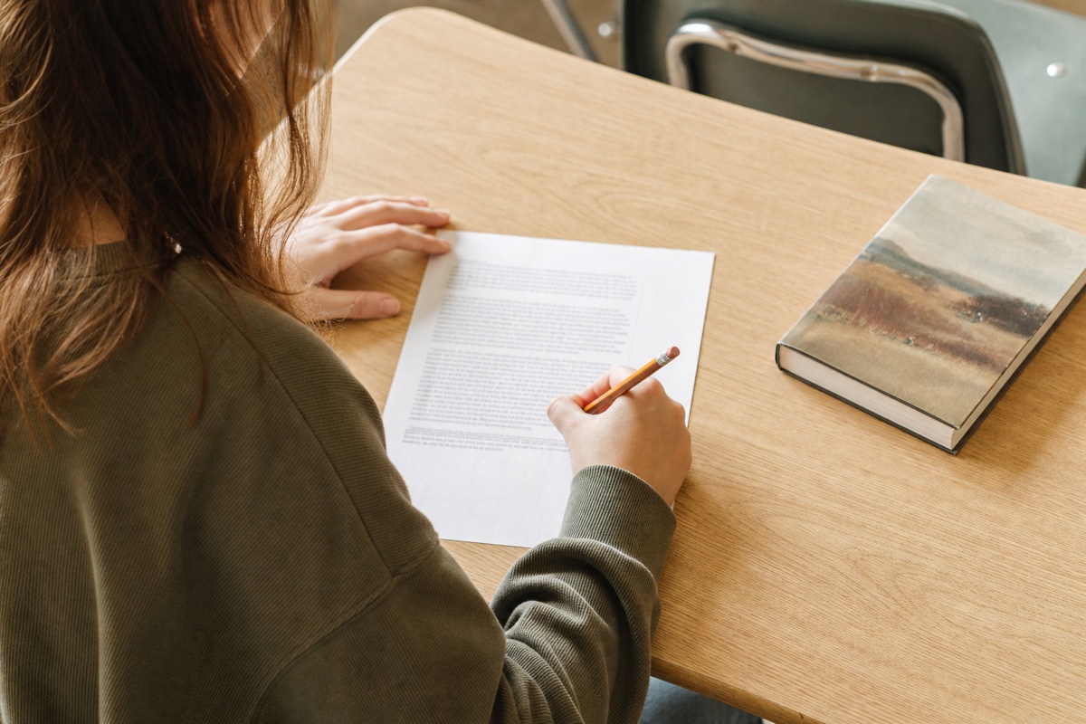 A student reading and annotating a longer text at a classroom desk.